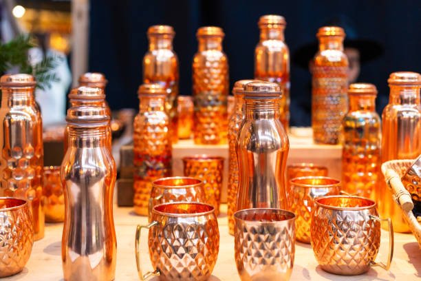 Retail display of an array of copper products, including cups and water bottles, for sale at the market.