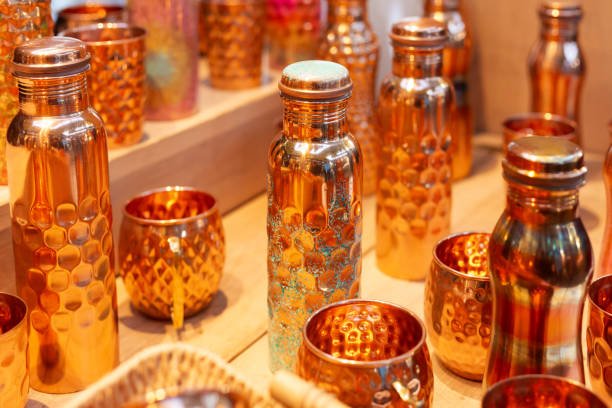 Retail display of an array of copper products, including cups and water bottles, for sale at the market.